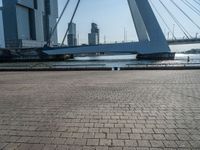 a yellow and white boat in the water next to buildings on a bridge with a few people around it