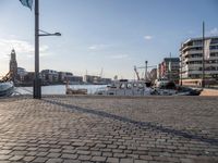 the walkway in a large boat dock next to a tall building on water, with boats docked nearby