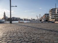 the walkway in a large boat dock next to a tall building on water, with boats docked nearby