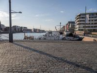 the walkway in a large boat dock next to a tall building on water, with boats docked nearby