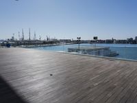 a wooden floor on top of a boat dock near the water and many docked sailboats