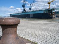 there is a boat docked in the port near a dock, and a post with it's ends at an angle of four