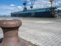 there is a boat docked in the port near a dock, and a post with it's ends at an angle of four