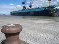 there is a boat docked in the port near a dock, and a post with it's ends at an angle of four