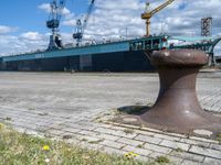 there is a boat docked in the port near a dock, and a post with it's ends at an angle of four