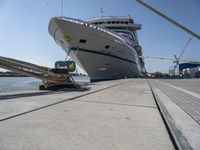 a white boat docked at the dock with some ropes on it's side and another ship in the background