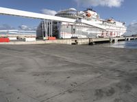 a large boat sitting by a dock with stairs leading to it's deck and a ramp leading up to the front