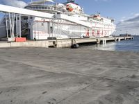 a large boat sitting by a dock with stairs leading to it's deck and a ramp leading up to the front