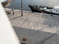 a boat and helicopter at the edge of a canal next to buildings and a body of water