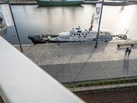 a large boat parked on top of a dock next to water's edge a city