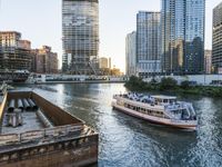 a large boat traveling down the river next to a big city skyline during the day