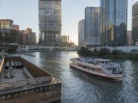 a large boat traveling down the river next to a big city skyline during the day