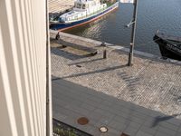 a large boat in the water near some buildings and a sidewalk with benches by it