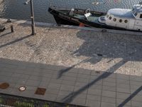 a large boat in the water near some buildings and a sidewalk with benches by it