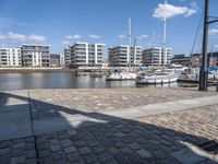 some boats are docked next to a riverbank and buildings in the background while sun shines on them