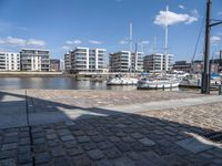 some boats are docked next to a riverbank and buildings in the background while sun shines on them