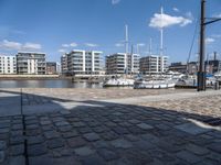 some boats are docked next to a riverbank and buildings in the background while sun shines on them