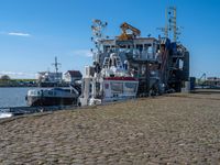 a tugboat sits at a dock with other boats nearby in the harbor area by a body of water