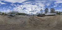 a 360 camera view looking up at some boats on dirt and water with a few trees in the background