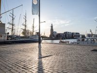 there are boats on the water that are sitting on the stone ground behind them, a clock tower and blue sky