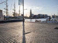 there are boats on the water that are sitting on the stone ground behind them, a clock tower and blue sky