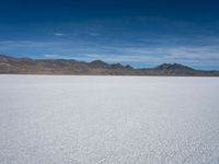 an image of snowboarders out on a flat surface in the desert near mountains