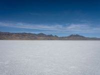 an image of snowboarders out on a flat surface in the desert near mountains