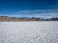 an image of snowboarders out on a flat surface in the desert near mountains