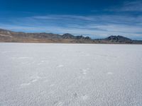 an image of snowboarders out on a flat surface in the desert near mountains