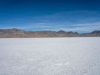 an image of snowboarders out on a flat surface in the desert near mountains