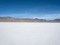 an image of snowboarders out on a flat surface in the desert near mountains