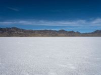 an image of snowboarders out on a flat surface in the desert near mountains