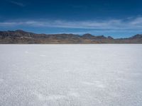 an image of snowboarders out on a flat surface in the desert near mountains