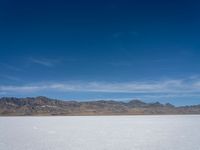 an image of snowboarders out on a flat surface in the desert near mountains