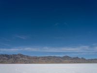 an image of snowboarders out on a flat surface in the desert near mountains