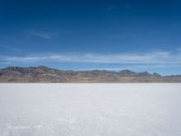 an image of snowboarders out on a flat surface in the desert near mountains