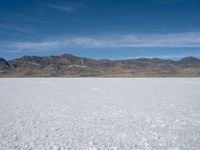 an image of snowboarders out on a flat surface in the desert near mountains