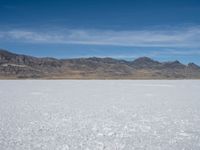 an image of snowboarders out on a flat surface in the desert near mountains