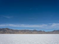 an image of snowboarders out on a flat surface in the desert near mountains