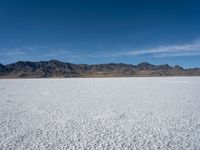 an image of snowboarders out on a flat surface in the desert near mountains