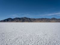 an image of snowboarders out on a flat surface in the desert near mountains