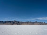 an image of snowboarders out on a flat surface in the desert near mountains