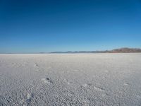 a barren plain with lots of snow and rocks, with a clear blue sky in the background