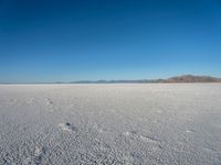 a barren plain with lots of snow and rocks, with a clear blue sky in the background