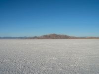 a barren plain with lots of snow and rocks, with a clear blue sky in the background