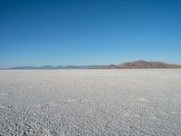 a barren plain with lots of snow and rocks, with a clear blue sky in the background