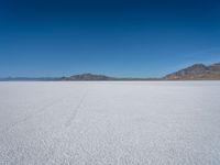 a large expanse that has some hills in the background and blue skies above it that is completely barren