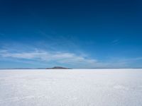 the salt has no clouds and a very small hill on it in the distance is a lake