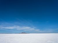 the salt has no clouds and a very small hill on it in the distance is a lake