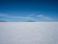 the salt has no clouds and a very small hill on it in the distance is a lake